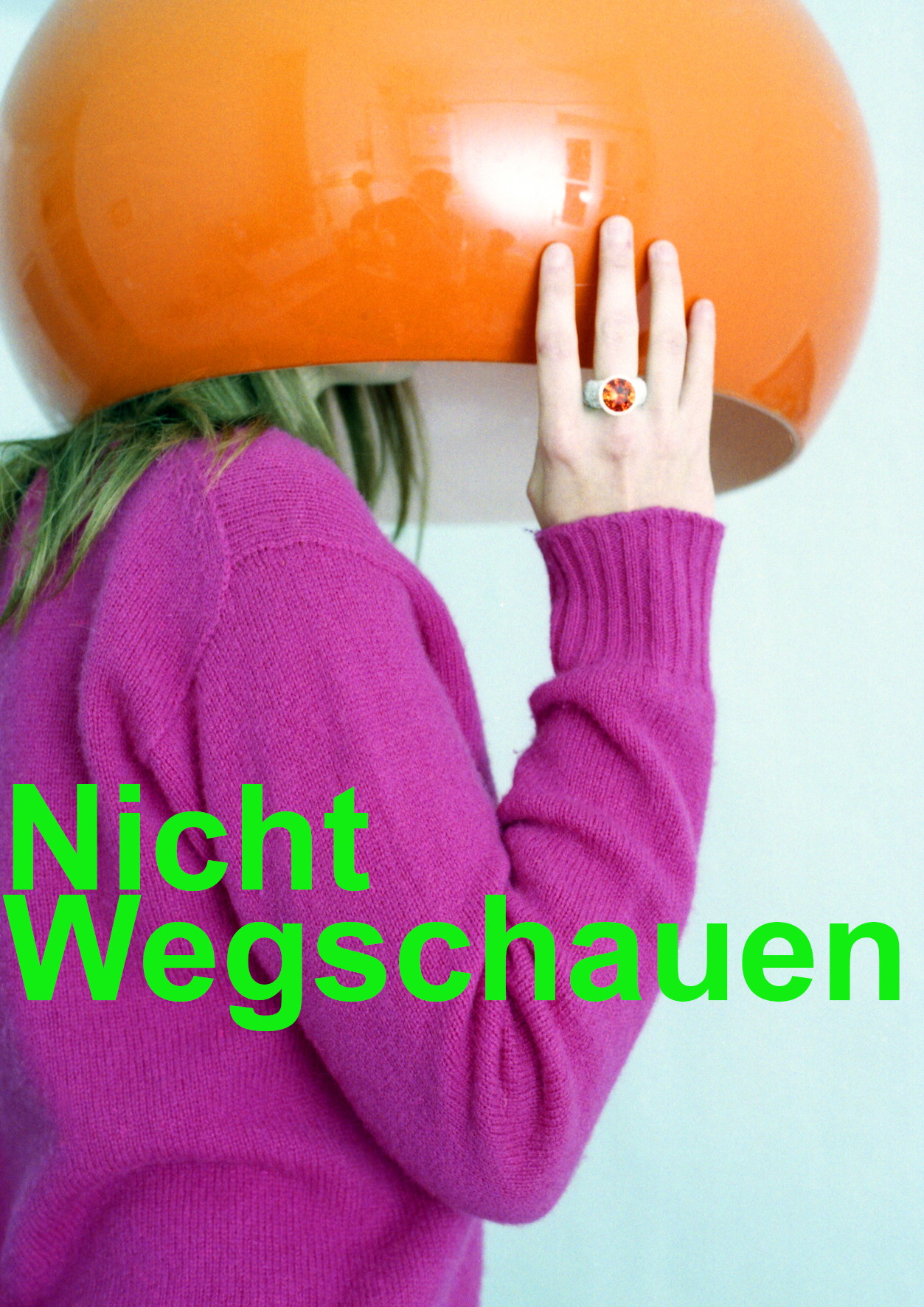 Frau steht in brombeerfarbenem Pulli steht mit dem Kopf unter einer orangefarbenen Retrolampe
