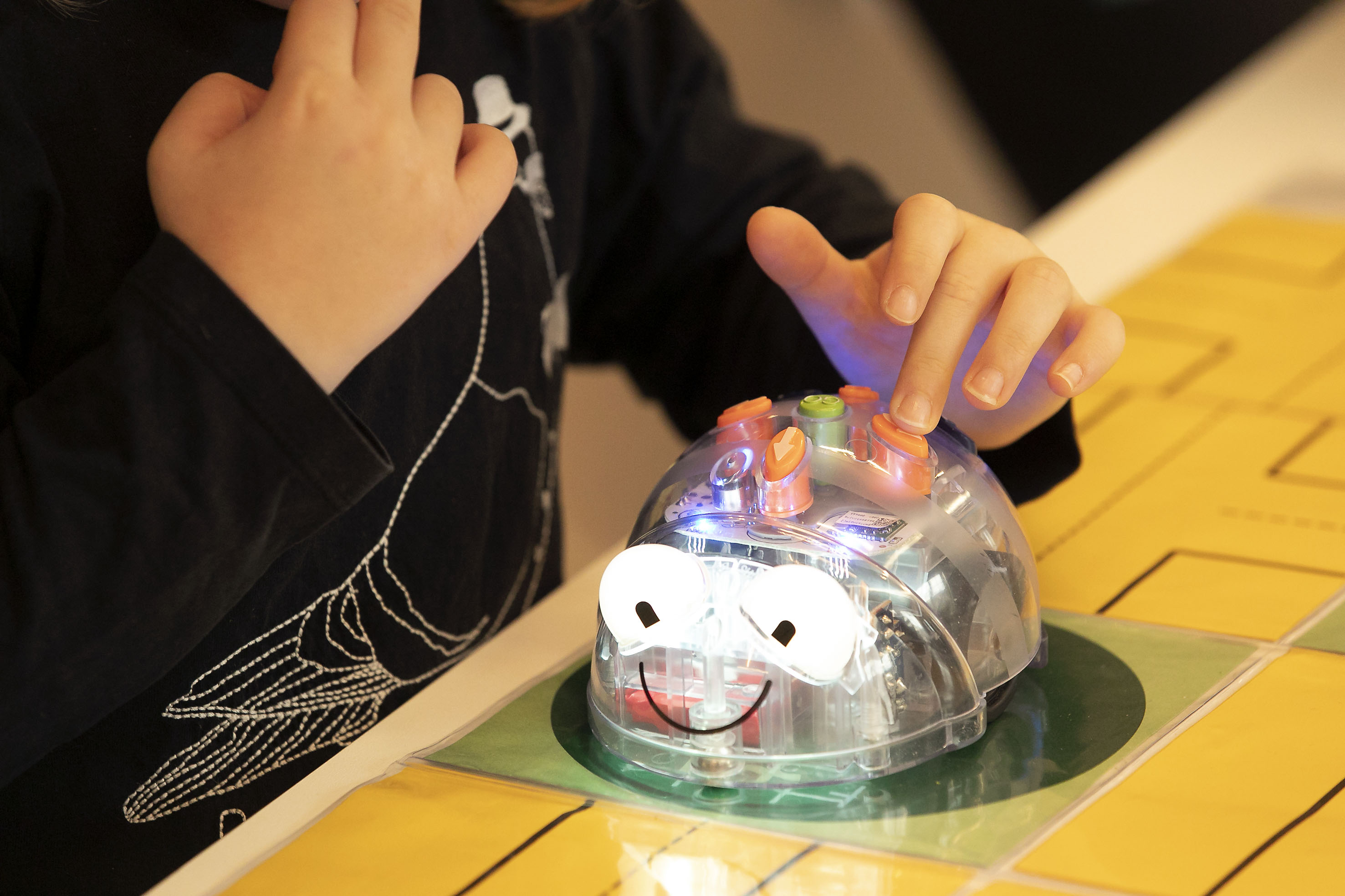 Ein Kind spielt mit einem BeeBot Roboter