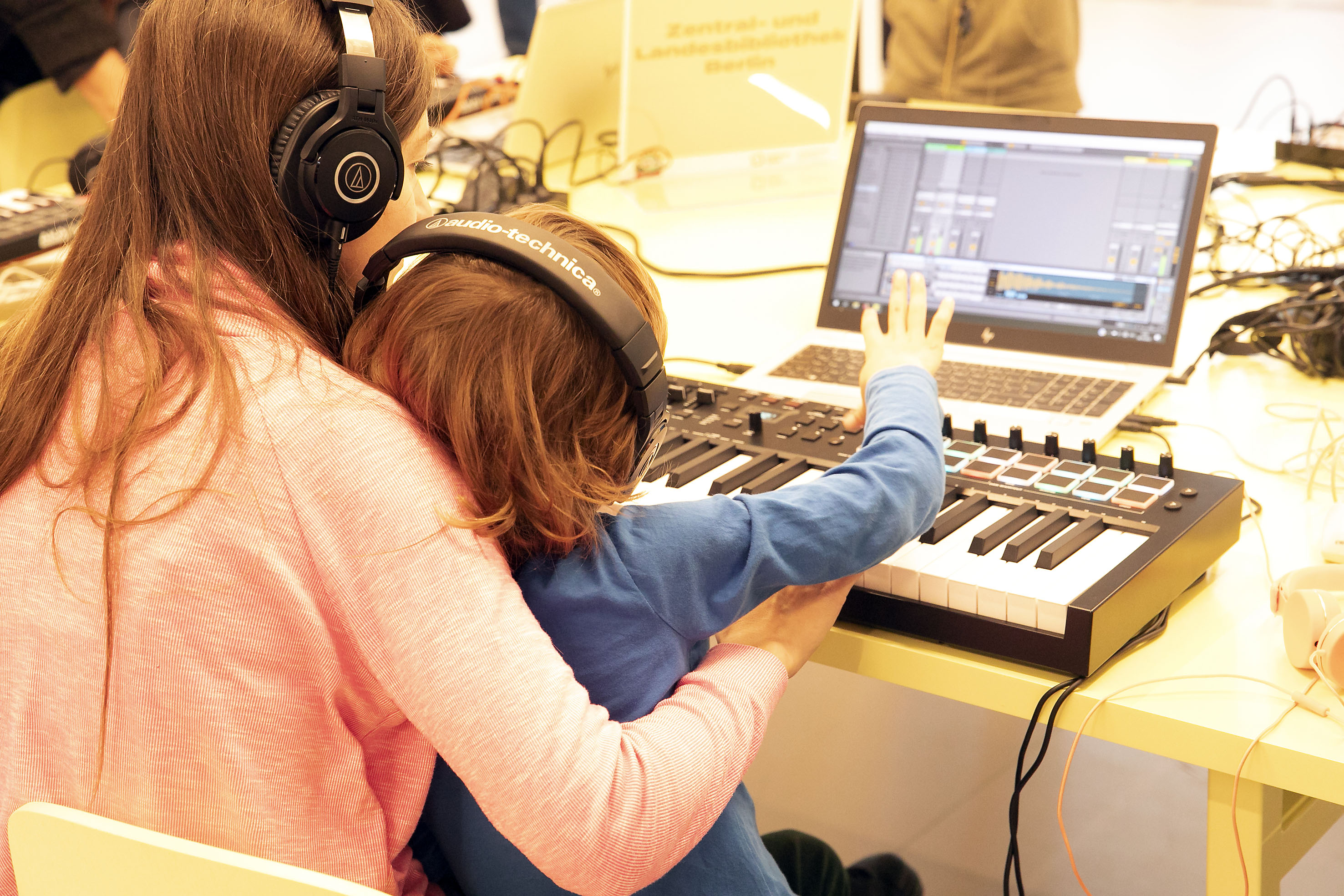 Eine Frau und ein Kind mit Kopfhörern machen elekronische Musik
