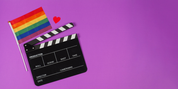 Eine Regenbogenflagge und eine Filmklappe auf violettem Hintergrund