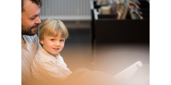 Ein Foto von einem Vater mit seinem Kind auf dem Schoß.