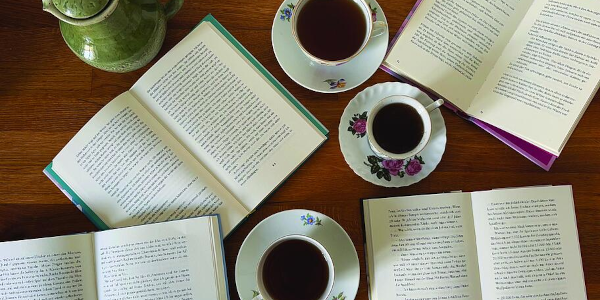 Ein Foto von aufgeschlagenen Büchern und Teetassen von oben fotografiert.