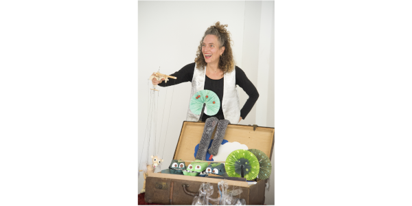 Foto einer Frau vor einem tisch mit gebastelten Puppentheater-Equipment