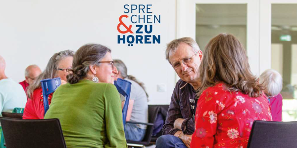 Eine Gruppe von Menschen sitzt beisammen und diskutiert.