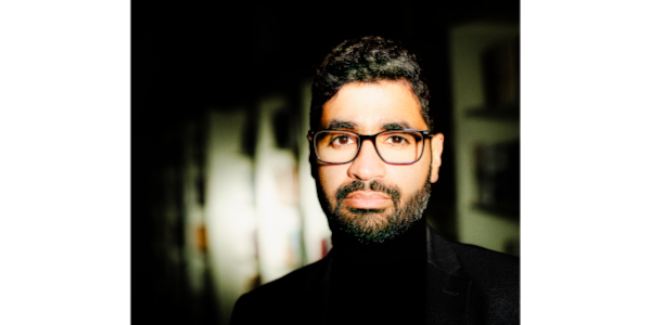 mystisch gehaltenes Portrait Foto von Mohamed Amjahid, einem mann mit schwarzen Haaren, kurzem Bart und Brille