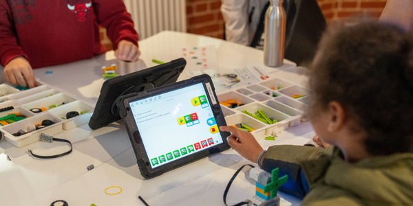 Kind vor Tabelt mit kindgerechter Programmier-Software auf der Anzeige.